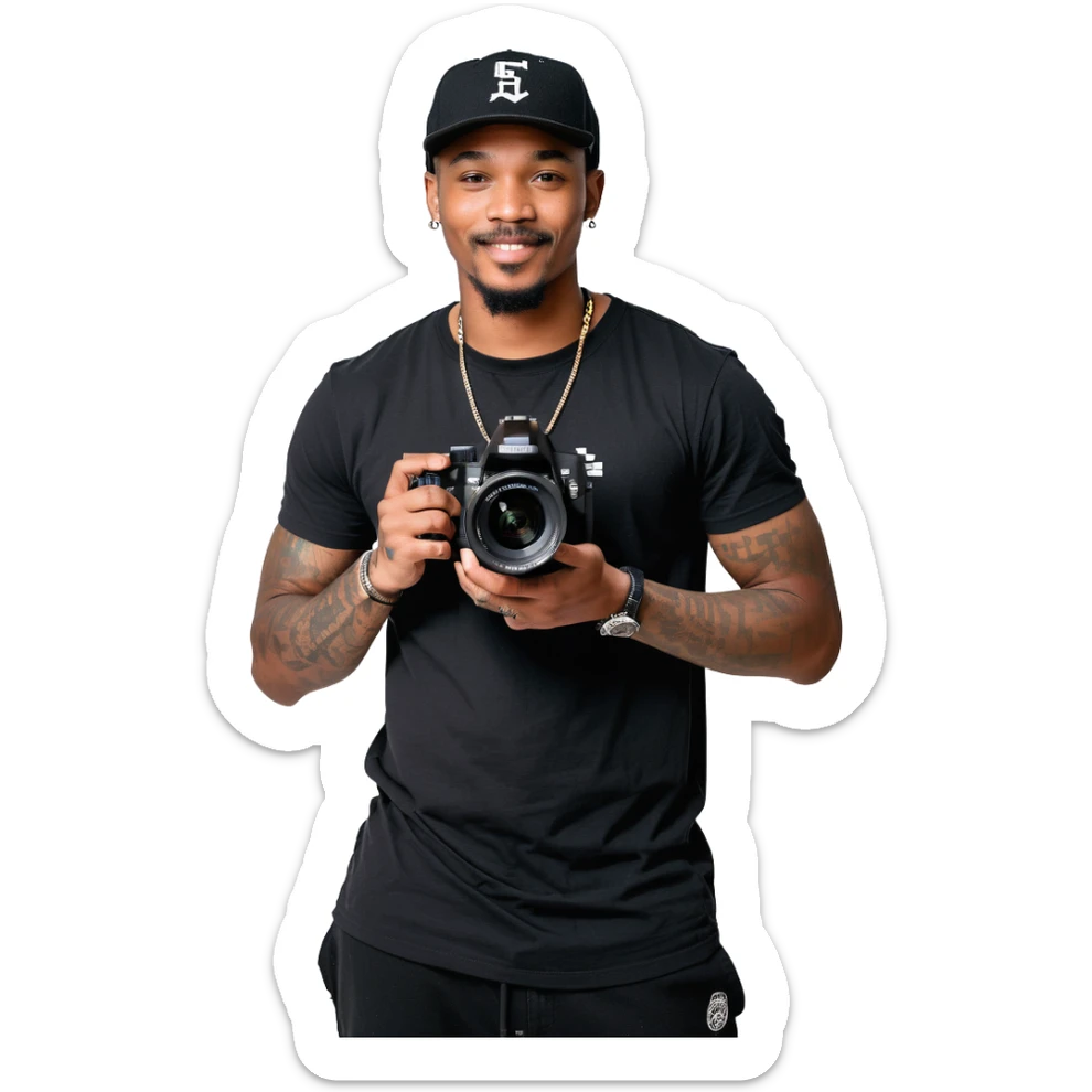 A young, black, South African, male cinematographer dressed in a black round neck t-shirt, black pants and black baseball cap holding a mirrorless dslr camera in one hand. Dark brown eyes. Bright white smile. Minimal facial hair — a small moustache connected to a goatee. Arms covered in tattoos. sticker