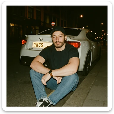 Grunge-style analog photo, London 2025, person inspired by the new reference image sitting on the curb in front of a Nissan GT 86, model pose, black t-shirt, jeans, Nike Air Jordan low, using flash, city street, analog grain, 5/8. sticker