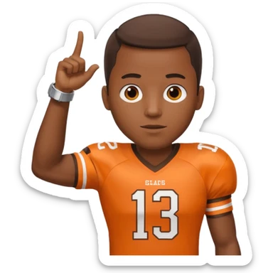 Black man in a brown and orange football jersey holding up his left arm with a watch on, pointing at the watch with his right hand sticker