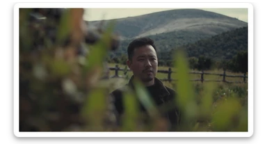 A portrait of a person in the foreground, blurred plants in the foreground (close to the camera), a wooden fence in the midground, rolling hills in the background, cinematic depth of field, layered composition, natural lighting sticker
