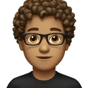 A boy with brown curly hair and black glasses with brown eyes and a black shirt sticker