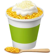 A white plastic cup filled whit yellow corn kernels, topped with grated cheese, white cream, chili powder, and a plastic spoon, with a hint of lime sticker