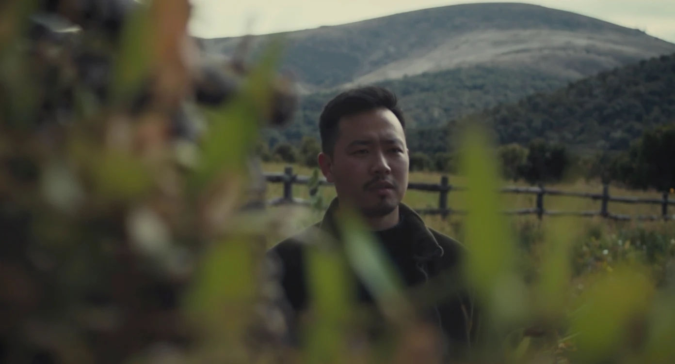 A portrait of a person in the foreground, blurred plants in the foreground (close to the camera), a wooden fence in the midground, rolling hills in the background, cinematic depth of field, layered composition, natural lighting emoji