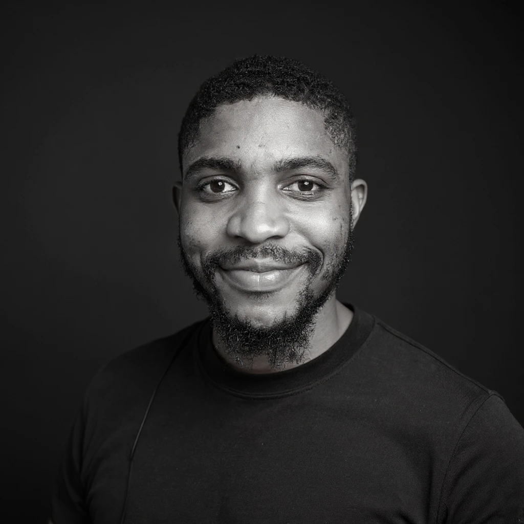A professional portrait of me in monochrome. Plain black crew neck shirt. Tailored to LinkedIn. Tech boy vibe (programmer). I’m a black man from Nigeria. Retain facial features from attached image. emoji