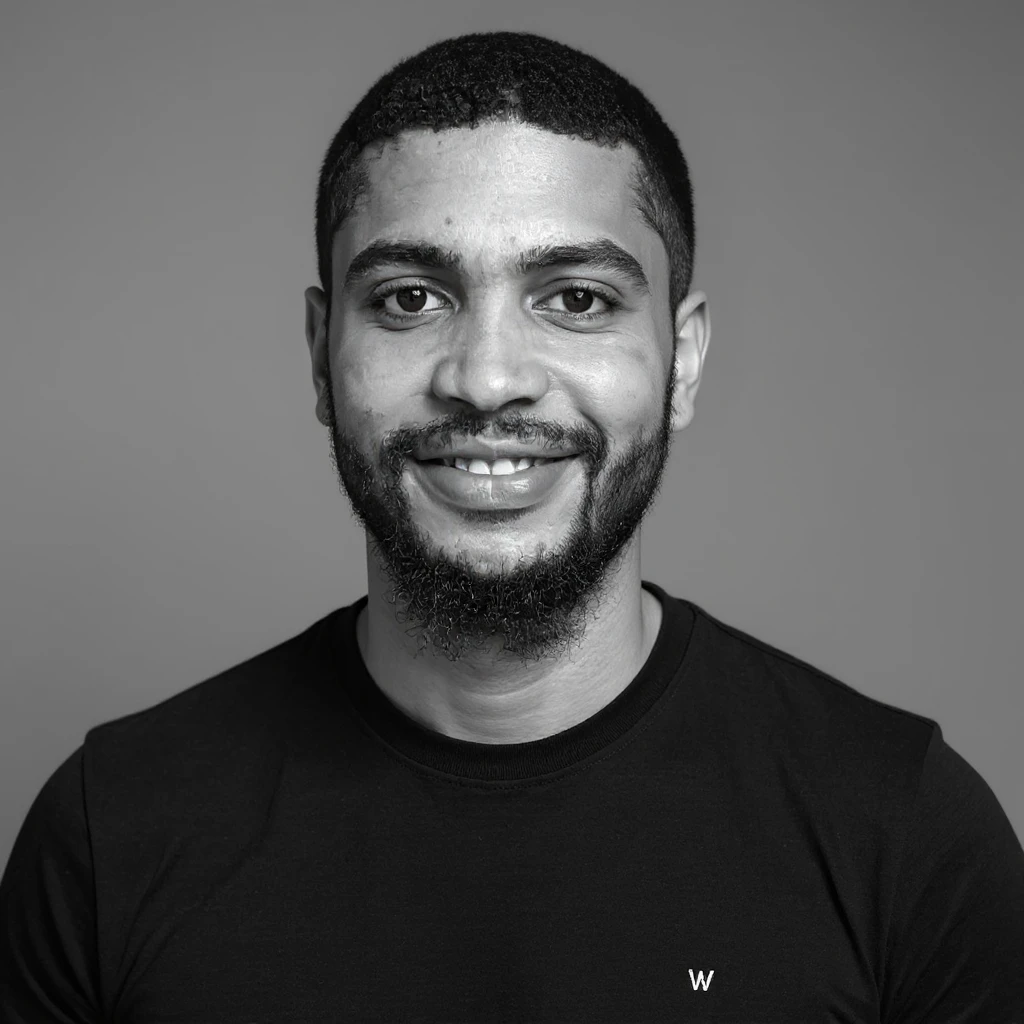 A professional portrait in monochrome. Plain black crew neck shirt. Tailored to LinkedIn. Tech boy vibe (programmer) emoji
