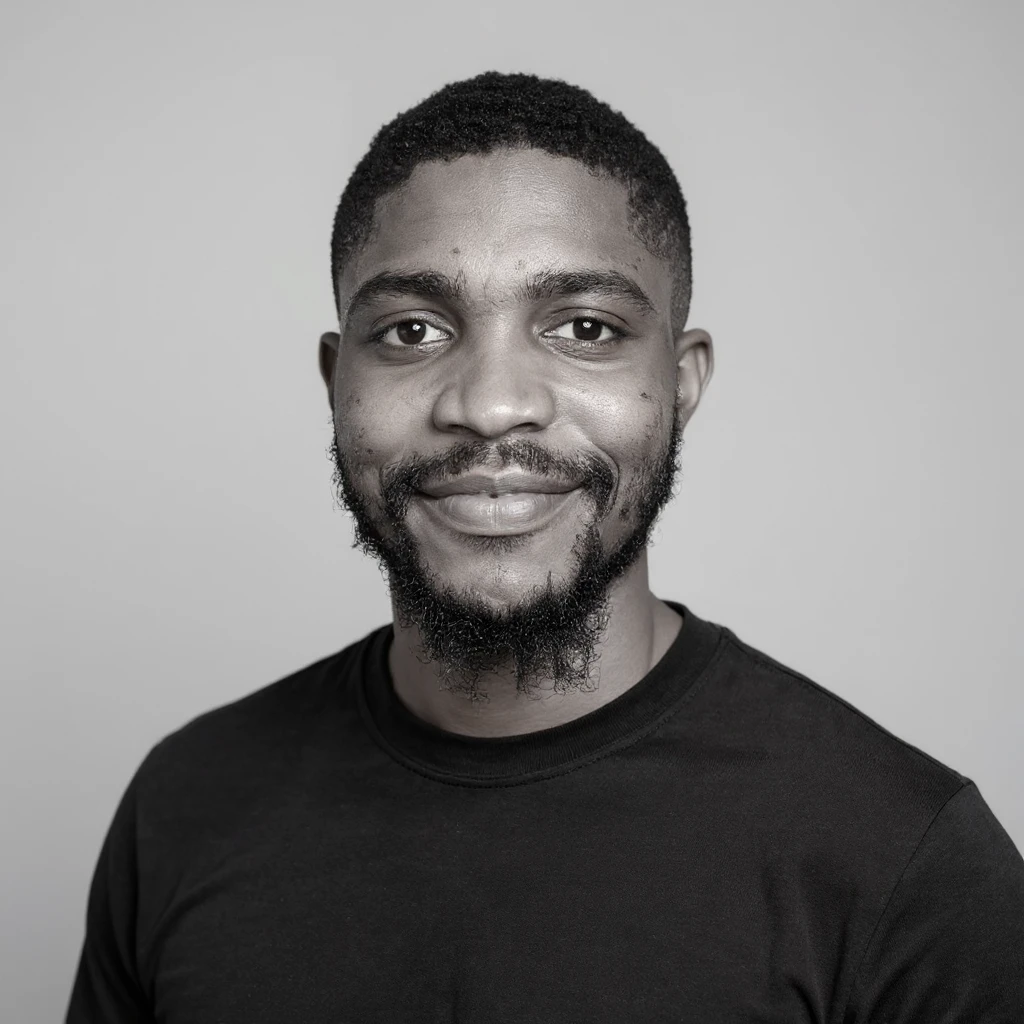 A professional portrait of me in monochrome. Plain black crew neck shirt. Tailored to LinkedIn. Tech boy vibe (programmer). I’m a black man from Nigeria. Retain facial features from attached image. Make face smoothie and healthy. No accessories. Light gray background to make subject more visible. emoji