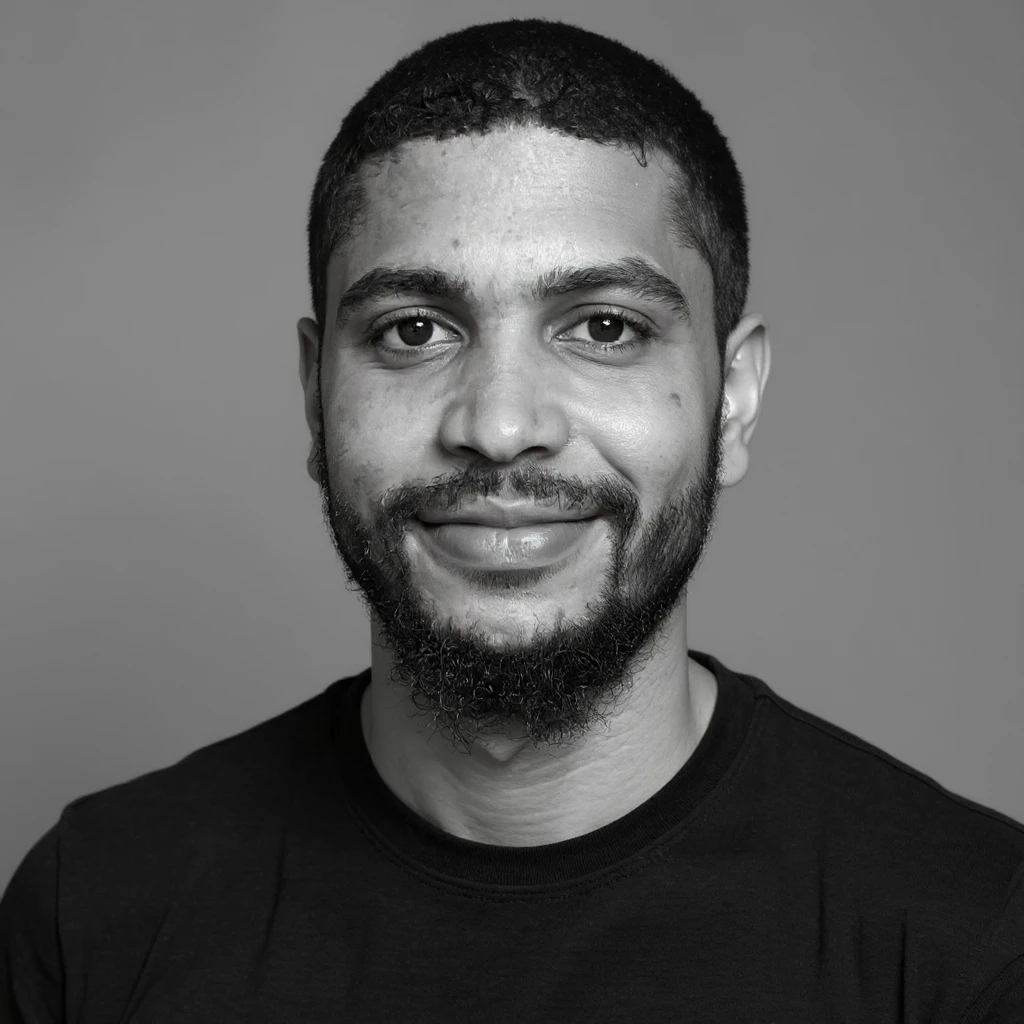 A professional portrait in monochrome. Plain black crew neck shirt. Tailored to LinkedIn. Tech boy vibe (programmer) emoji