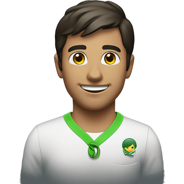 The image shows a young man with short dark hair and facial hair. He is smiling and wearing a white shirt with a green lanyard or badge. There is a dark background behind him with some red text visible. emoji